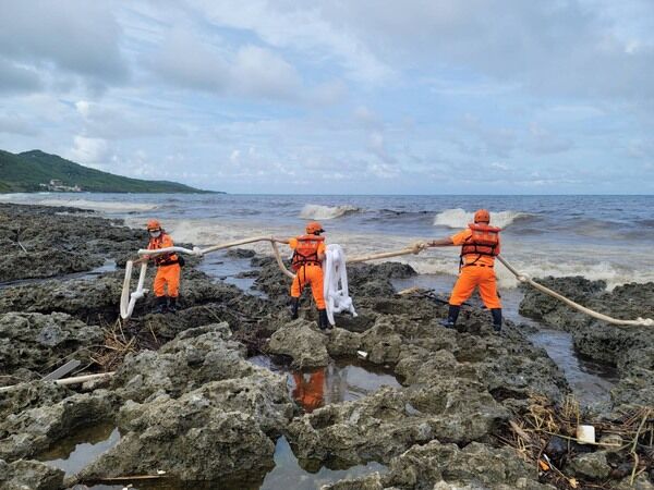 圖二  海巡人員於岸際布放吸油索圍堵油污